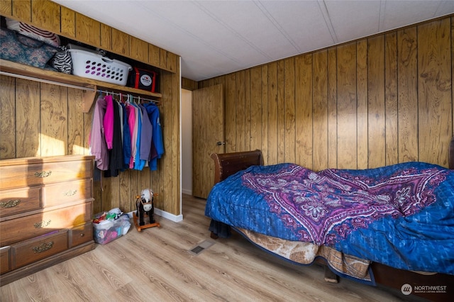 bedroom with light hardwood / wood-style floors, a closet, and wood walls