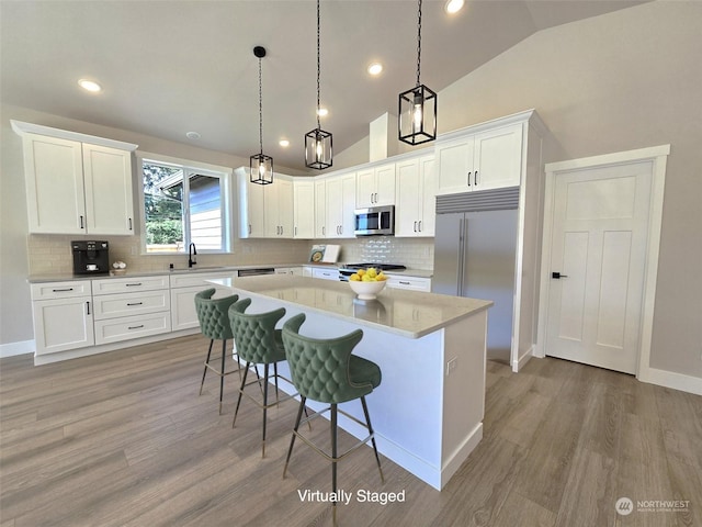 kitchen with a kitchen island, lofted ceiling, sink, hanging light fixtures, and stainless steel appliances