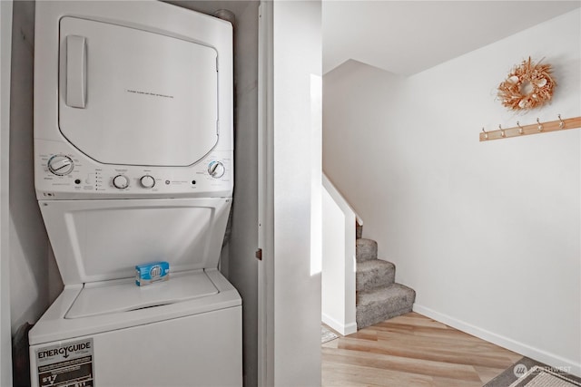 laundry area featuring stacked washer and clothes dryer and light hardwood / wood-style flooring