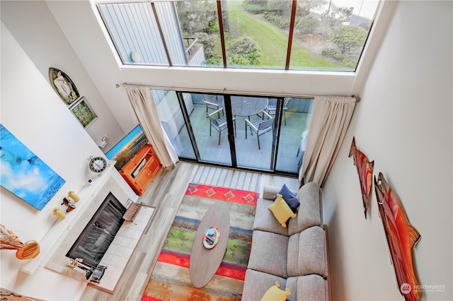 living room featuring wood-type flooring, a tile fireplace, and a high ceiling