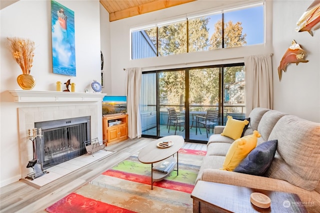 living room featuring a high ceiling, a tile fireplace, and light hardwood / wood-style flooring