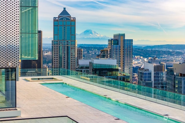 view of swimming pool featuring a mountain view, a community hot tub, and a patio