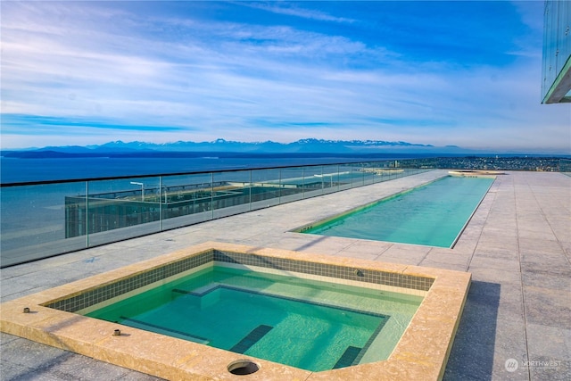 view of pool featuring an in ground hot tub and a water and mountain view