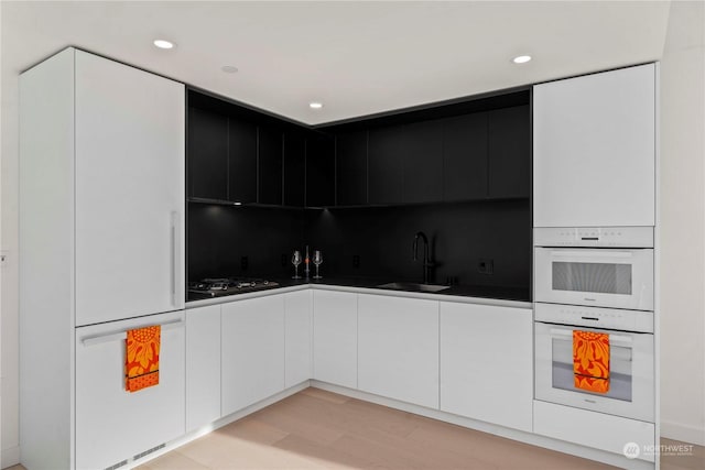 kitchen with sink, light hardwood / wood-style flooring, double oven, black gas cooktop, and white cabinets