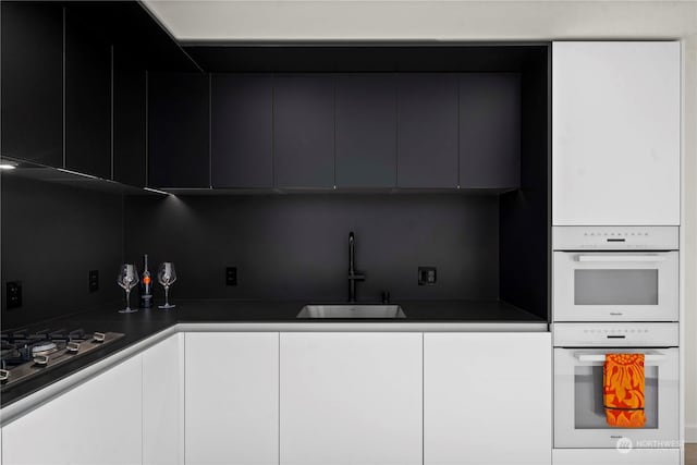 kitchen with sink, tasteful backsplash, gas cooktop, white double oven, and white cabinets