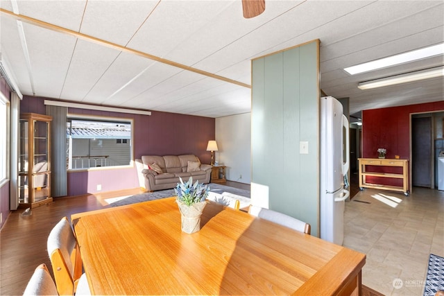 dining room featuring ceiling fan and wood walls