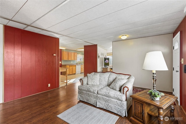 living room with hardwood / wood-style floors, a paneled ceiling, and wood walls