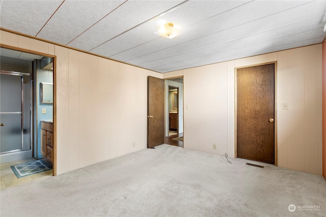 carpeted spare room featuring wood walls