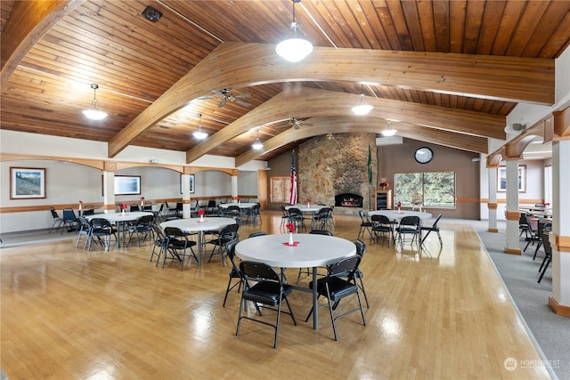 dining space with a stone fireplace, wood ceiling, vaulted ceiling, ceiling fan, and light hardwood / wood-style floors