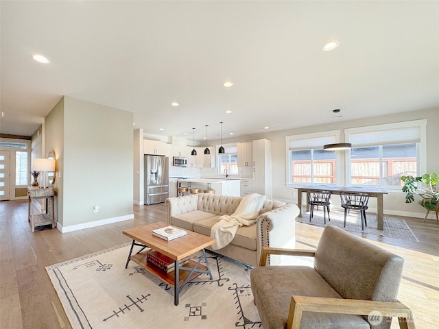 living room featuring sink, a healthy amount of sunlight, and light hardwood / wood-style flooring