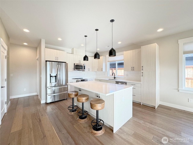kitchen featuring appliances with stainless steel finishes, pendant lighting, a wealth of natural light, a center island, and a kitchen bar