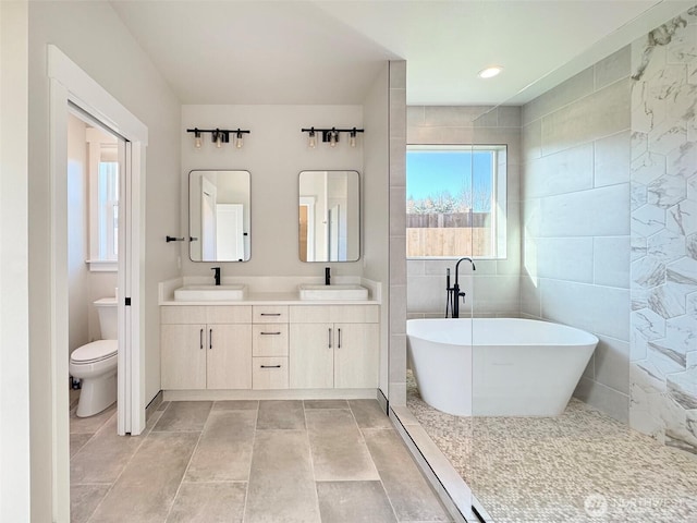 bathroom with tile walls, vanity, a washtub, and toilet