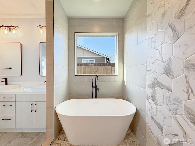 bathroom with tile walls, a tub, and vanity