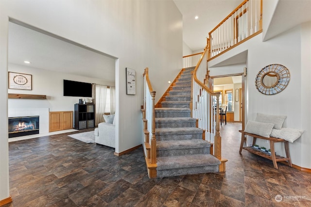 stairs with a tiled fireplace and a high ceiling