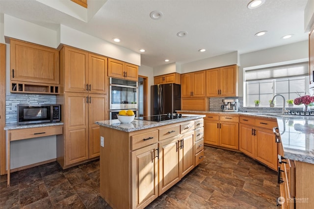 kitchen featuring a kitchen island, sink, backsplash, black appliances, and light stone countertops