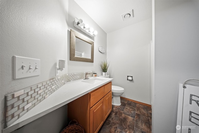 bathroom featuring tasteful backsplash, vanity, and toilet