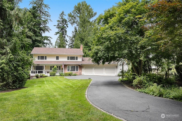 colonial inspired home featuring a garage, a front lawn, and covered porch