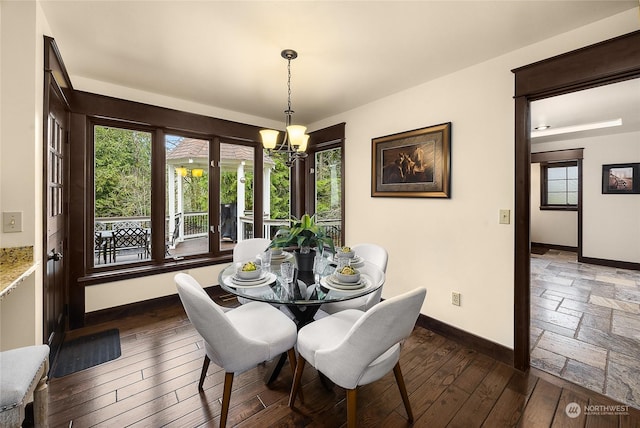 dining space with dark hardwood / wood-style flooring and an inviting chandelier