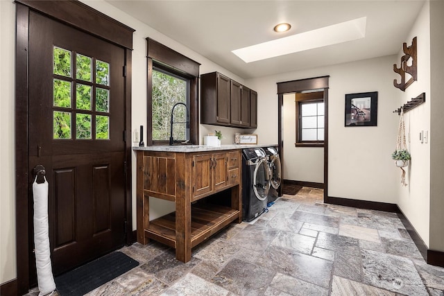 washroom featuring washer and dryer, sink, a skylight, and cabinets