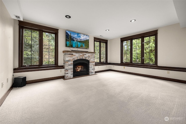 unfurnished living room featuring carpet flooring, a wealth of natural light, and a fireplace