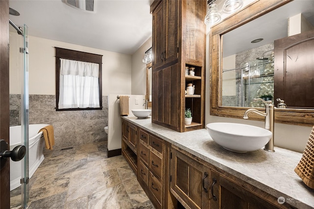 bathroom featuring tile walls, vanity, toilet, and walk in shower