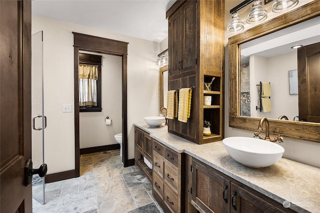 bathroom with vanity, toilet, and a shower with door