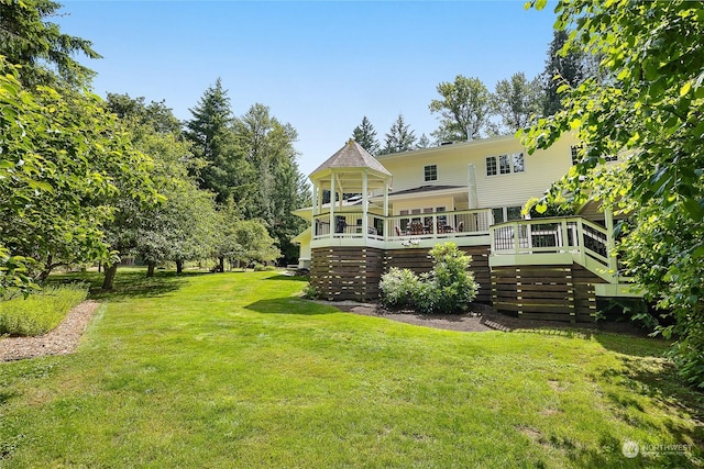 rear view of house with a wooden deck and a lawn