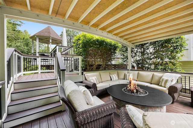 wooden terrace featuring an outdoor living space with a fire pit