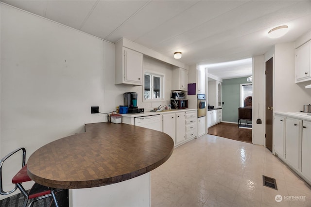 kitchen featuring wall oven, white cabinets, dishwasher, and kitchen peninsula