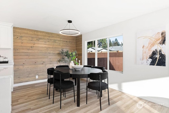 dining room with light wood-type flooring and wooden walls