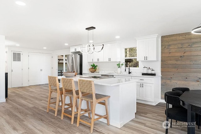 kitchen featuring white cabinetry, a center island, hanging light fixtures, and stainless steel refrigerator