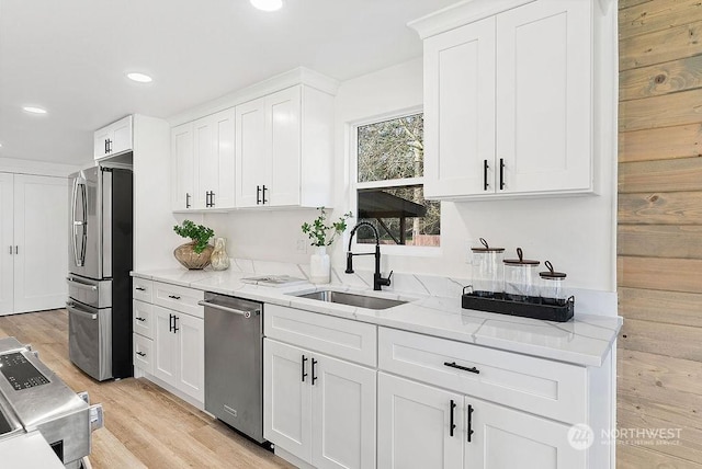 kitchen with sink, stainless steel appliances, white cabinets, and light stone countertops