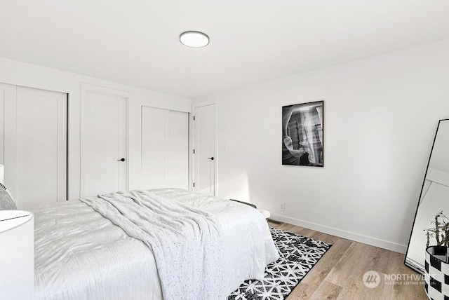 bedroom with two closets and light hardwood / wood-style flooring