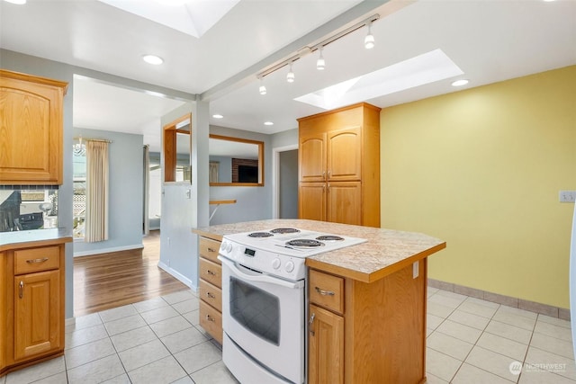 kitchen with electric stove, a skylight, a kitchen island, and light tile patterned floors