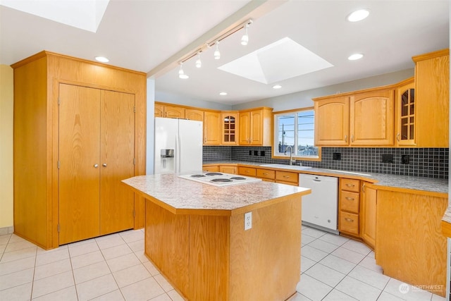 kitchen with a kitchen island, backsplash, white appliances, and a skylight