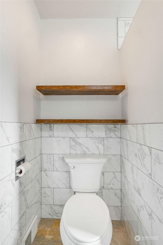 bathroom with tile walls and toilet