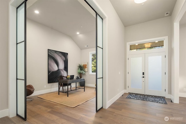 foyer with light wood-type flooring, vaulted ceiling, and french doors