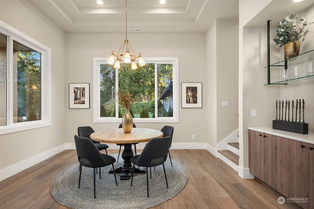 dining space featuring hardwood / wood-style flooring, a chandelier, and a tray ceiling