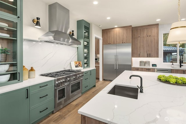 kitchen with light stone countertops, sink, premium appliances, and island exhaust hood