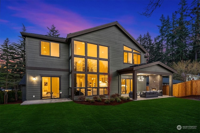 back house at dusk featuring a patio, outdoor lounge area, and a yard