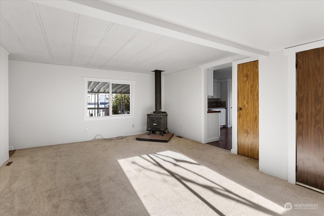 unfurnished bedroom with a wood stove and carpet