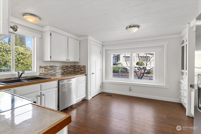 kitchen featuring stainless steel dishwasher, sink, backsplash, dark wood-type flooring, and white cabinets