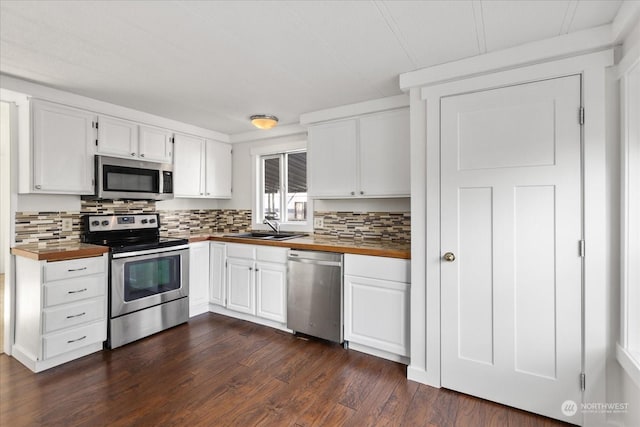 kitchen featuring sink, backsplash, white cabinetry, butcher block countertops, and stainless steel appliances