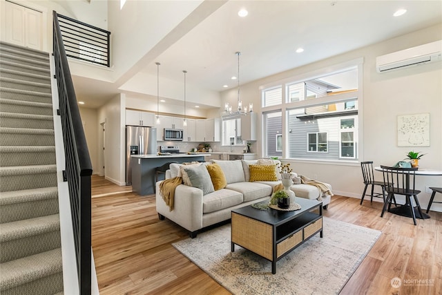 living room with an inviting chandelier, light hardwood / wood-style flooring, and an AC wall unit