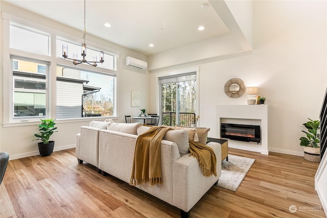 living room with a notable chandelier, light hardwood / wood-style flooring, and a wall unit AC