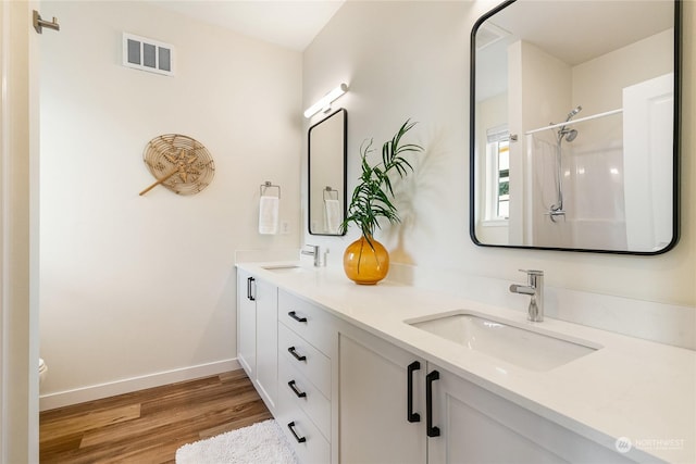 bathroom featuring hardwood / wood-style flooring, vanity, and walk in shower