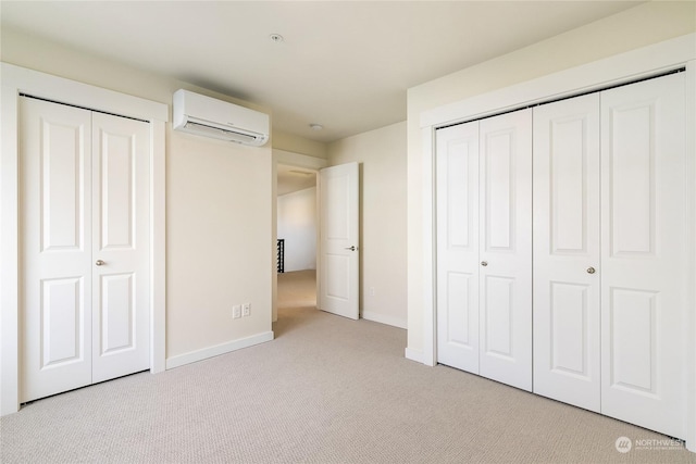 unfurnished bedroom featuring a wall mounted air conditioner, two closets, and light colored carpet