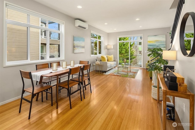 dining area featuring a wall mounted air conditioner, plenty of natural light, and light hardwood / wood-style floors