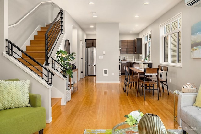 living room featuring a wall unit AC and light hardwood / wood-style flooring