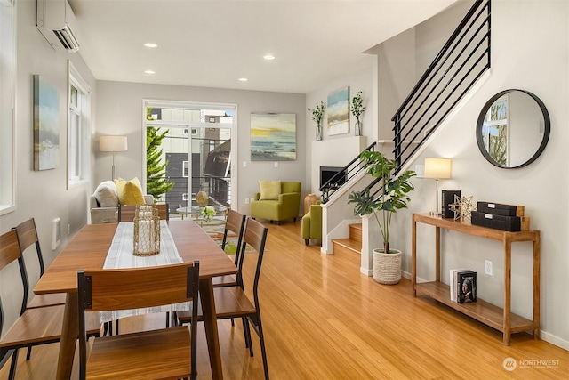 dining room featuring a wall mounted AC and light hardwood / wood-style floors